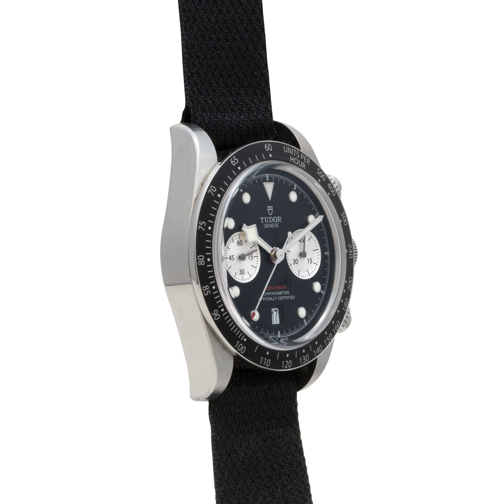 The TUDOR Black Bay Chronograph, featuring a black case, black fabric strap, and two white subdials, is shown from an angled view.