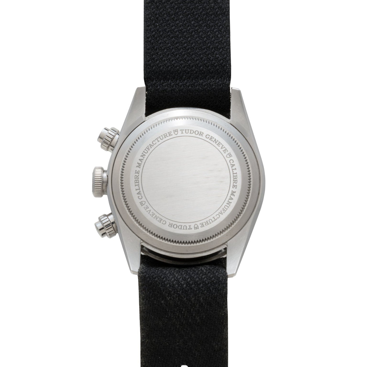 The TUDOR Black Bay Chronograph features a silver case back with engraved text, black fabric strap, and two side push buttons, shown from above.