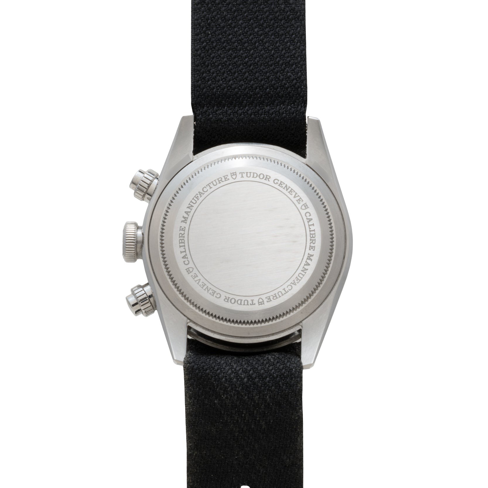 The TUDOR Black Bay Chronograph features a silver case back with engraved text, black fabric strap, and two side push buttons, shown from above.
