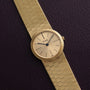 18K Yellow Gold Dress Watch by Piaget with a textured band displayed on a dark leather surface.
