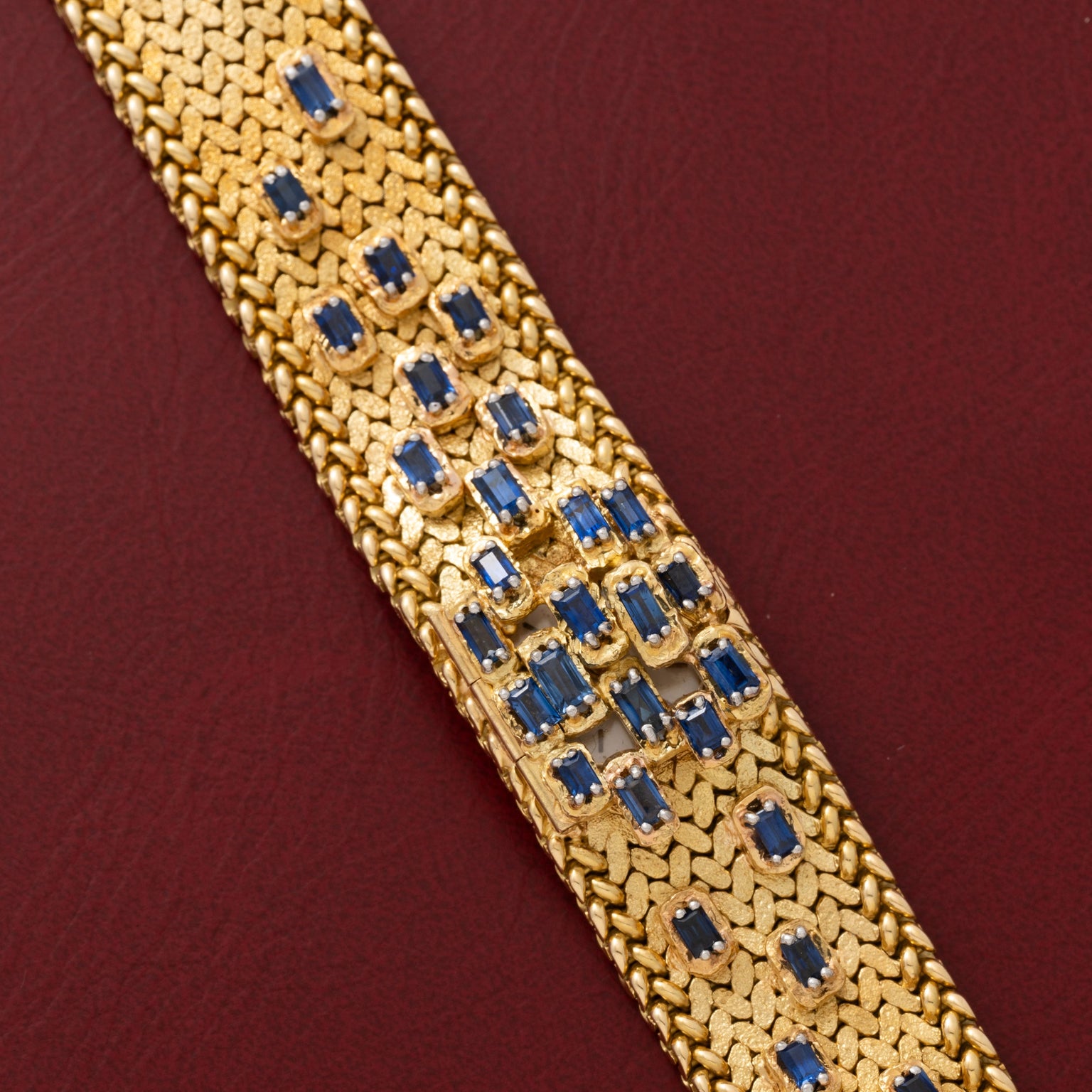 Patek Philippe Yellow Gold Integrated Dress Watch displayed on a maroon leather surface.
