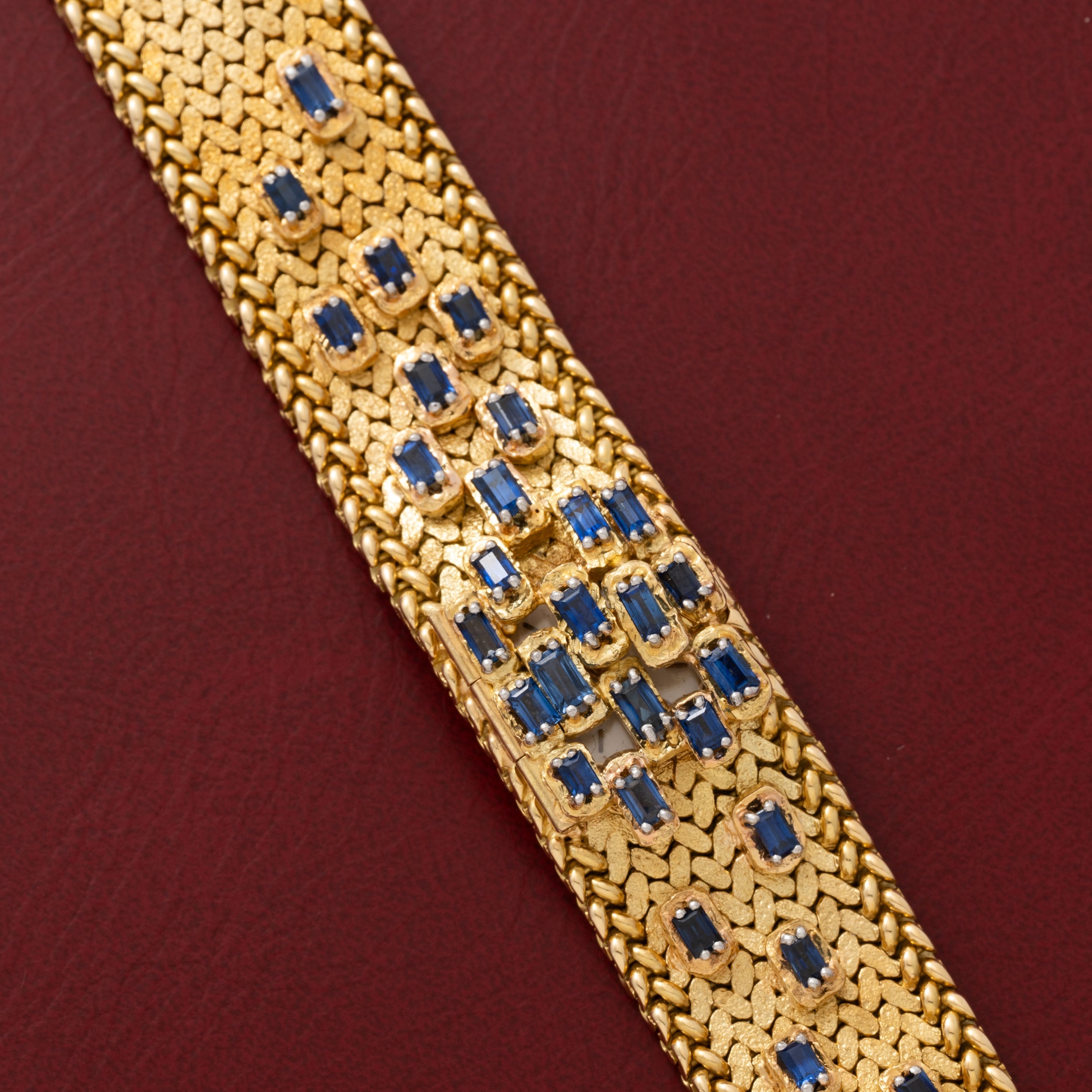 Patek Philippe Yellow Gold Integrated Dress Watch displayed on a maroon leather surface.