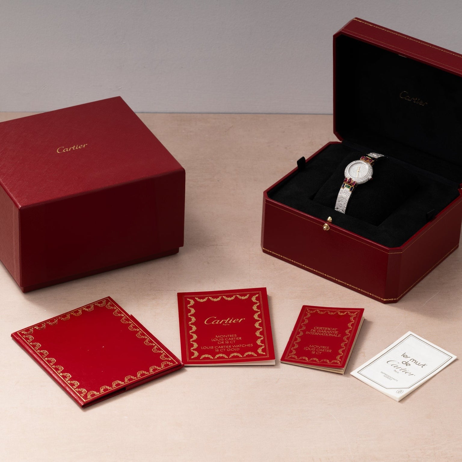 Cartier Colisee Tutti Frutti Diamond watch displayed in an open red box, with matching papers and booklets neatly arranged beside it.