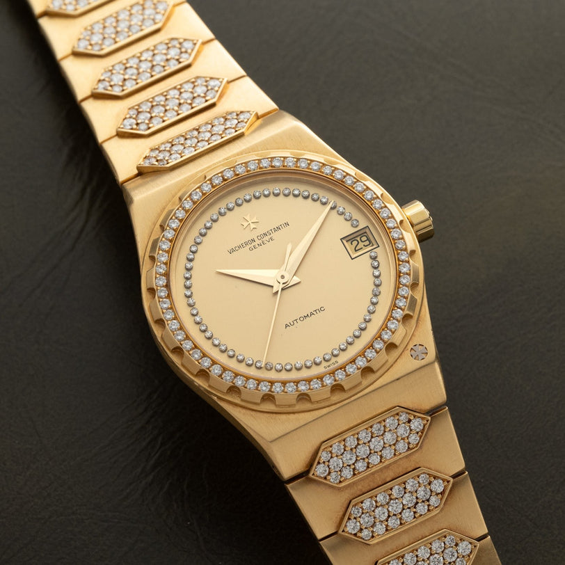 The Vacheron Constantin 222 is a gold wristwatch featuring diamond accents on the bezel and bracelet, and displays the date at 3 oclock.