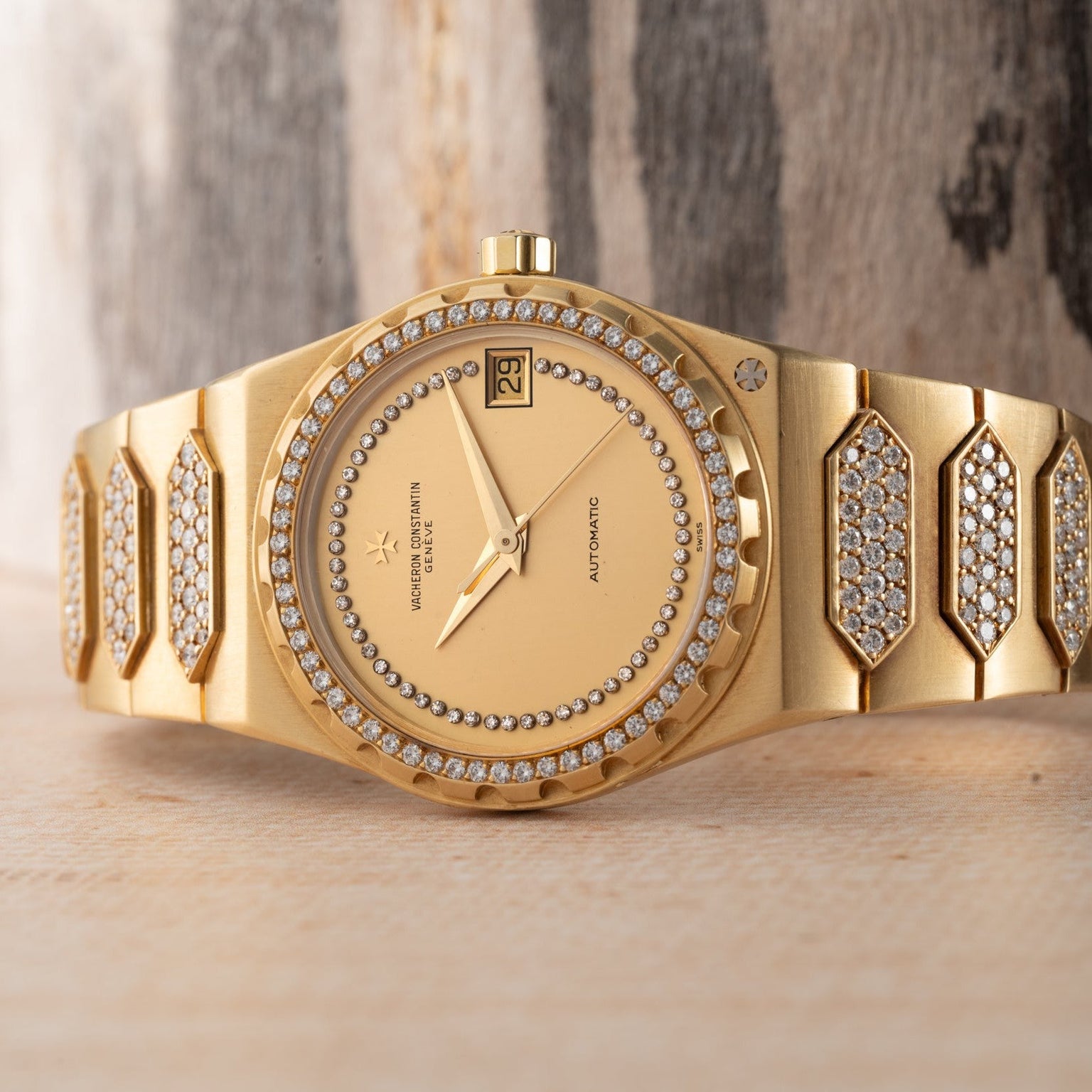The Vacheron Constantin 222 luxury wristwatch, featuring diamond accents on the band and bezel, is displayed on a wooden surface.