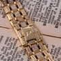 Close-up of the Piaget Polo Pave gold and diamond watch bracelet resting on an open book with visible text.
