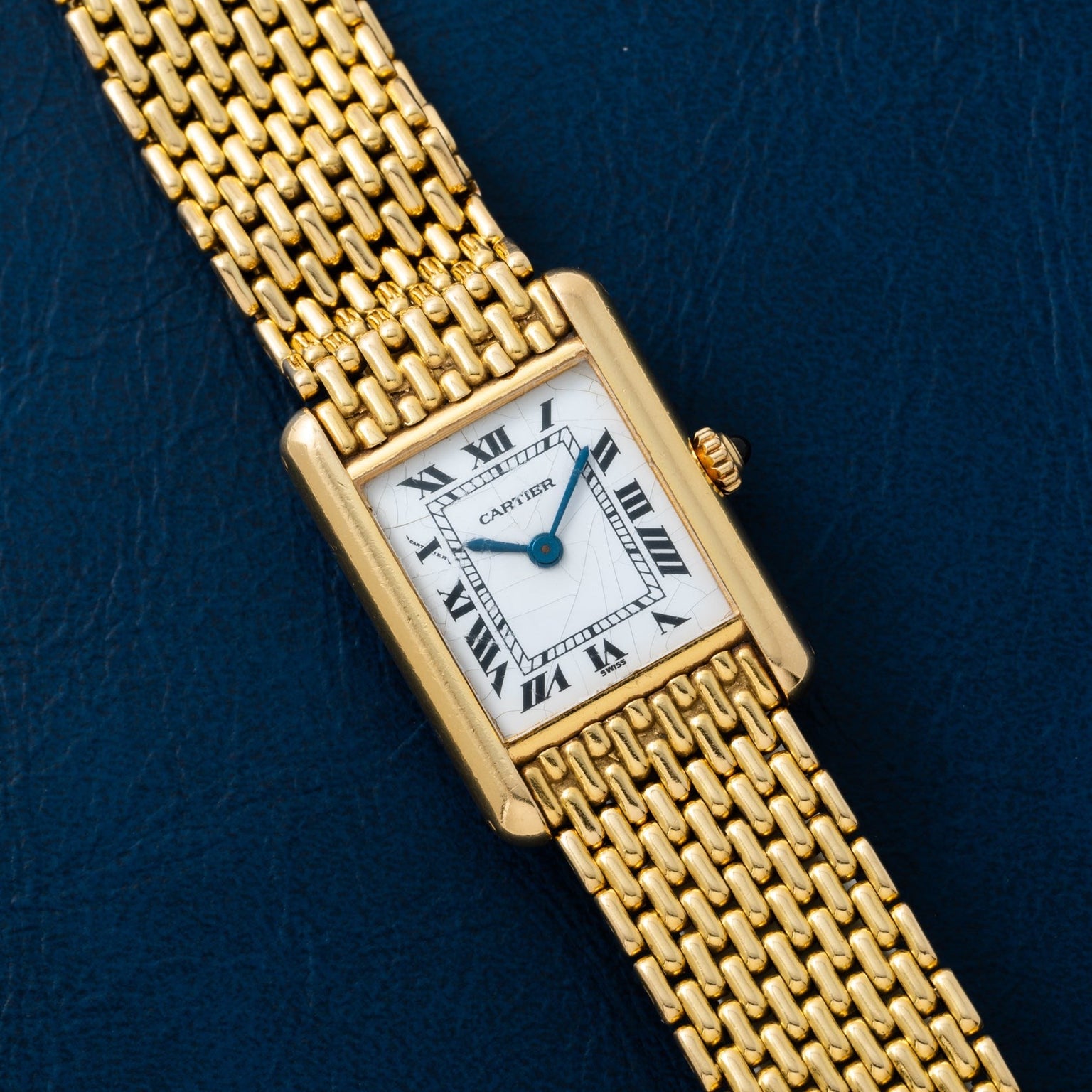 The Cartier Tank Louis features a rectangular gold case and Roman numerals on a dark blue dial.