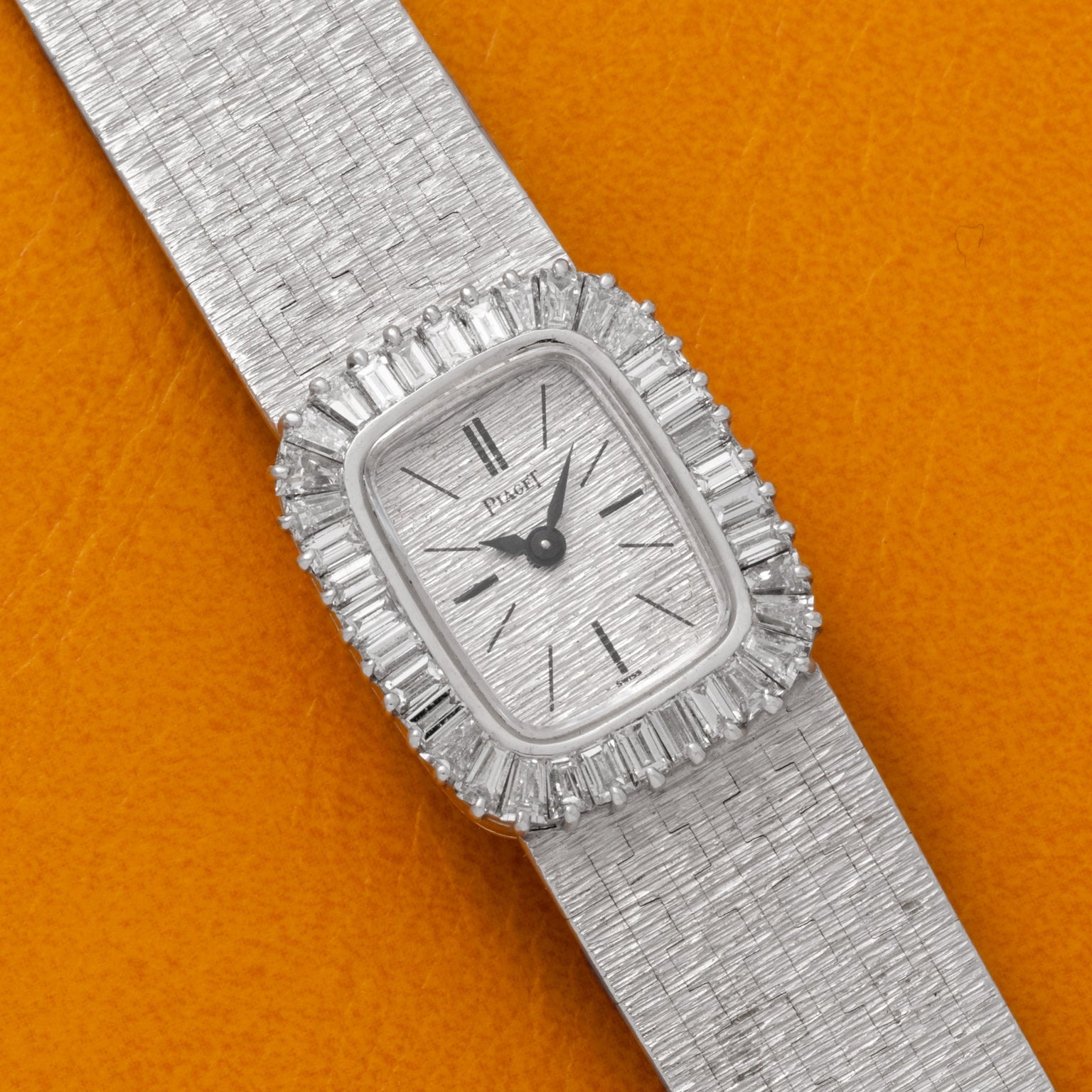 White Gold Bark Diamond Dress Watch by Piaget with diamond accents displayed on an orange textured background.