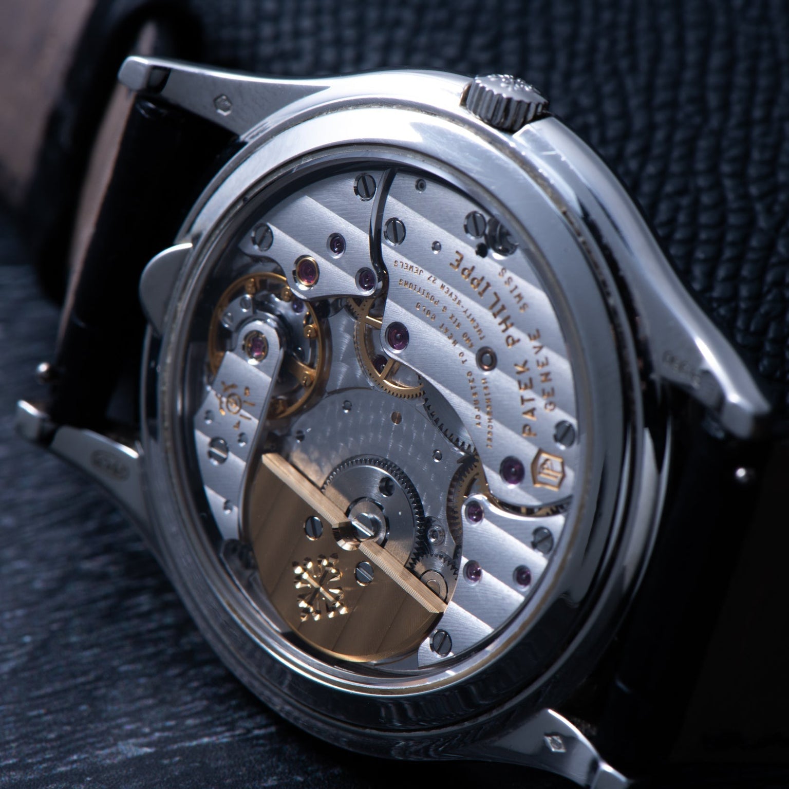 Close-up of a Patek Philippe Perpetual Calendar watch showcasing its exposed mechanical movement with intricate gears and detailed engravings.