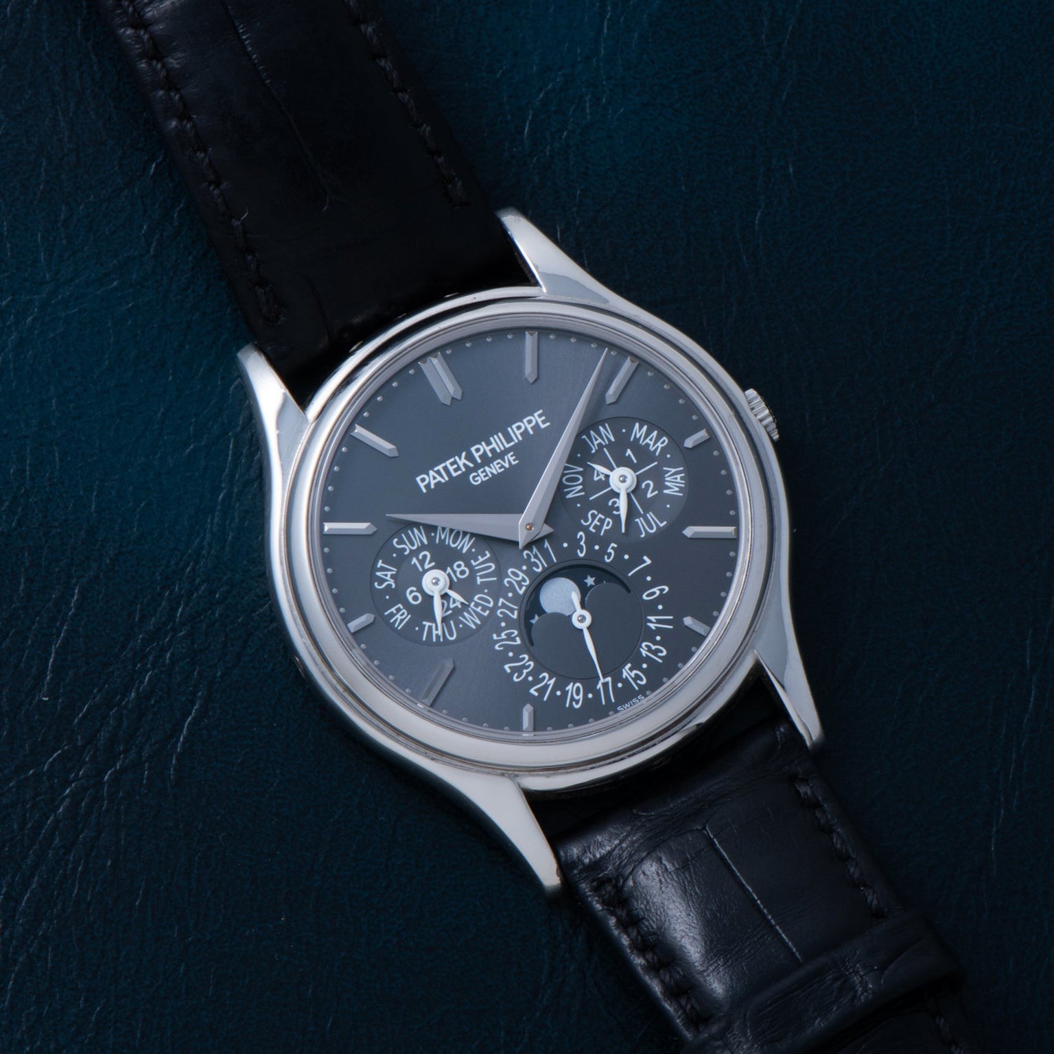 A Patek Philippe Perpetual Calendar wristwatch featuring a black leather strap and a dark face with multiple dials and indicators.
