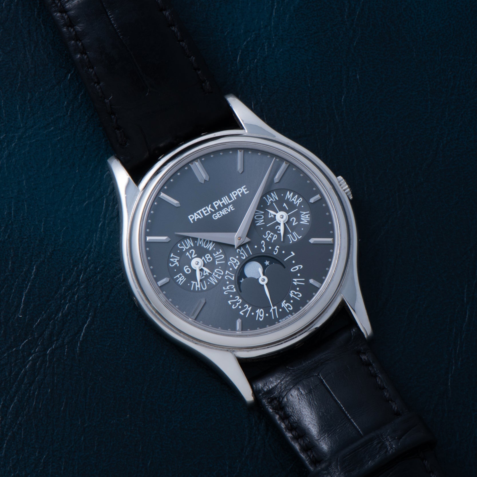 A Patek Philippe Perpetual Calendar wristwatch featuring a black leather strap and a dark face with multiple dials and indicators.