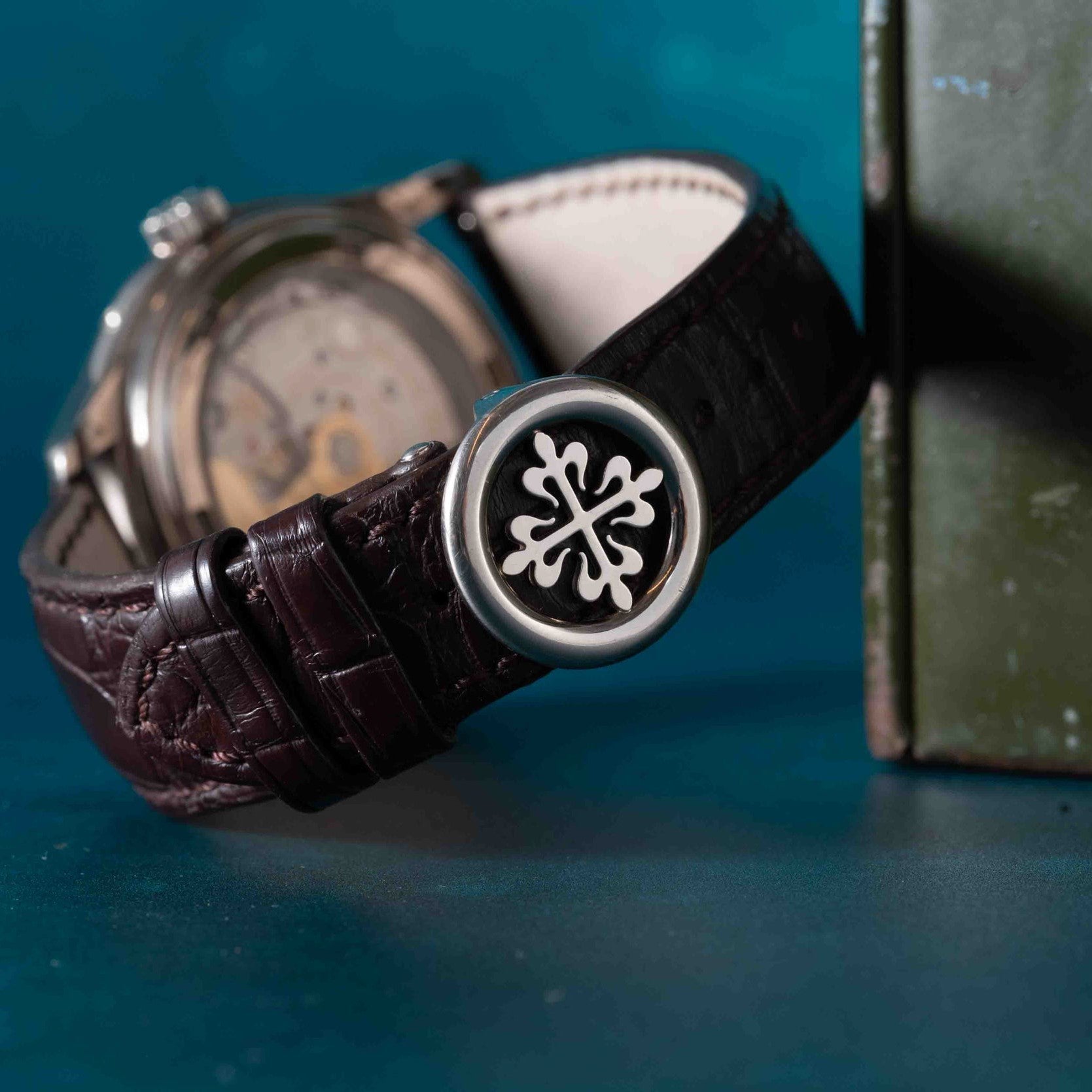 Close-up of the Patek Philippe Annual Calendar Moonphase, a luxury watch with a brown leather strap and decorative clasp featuring a white emblem.