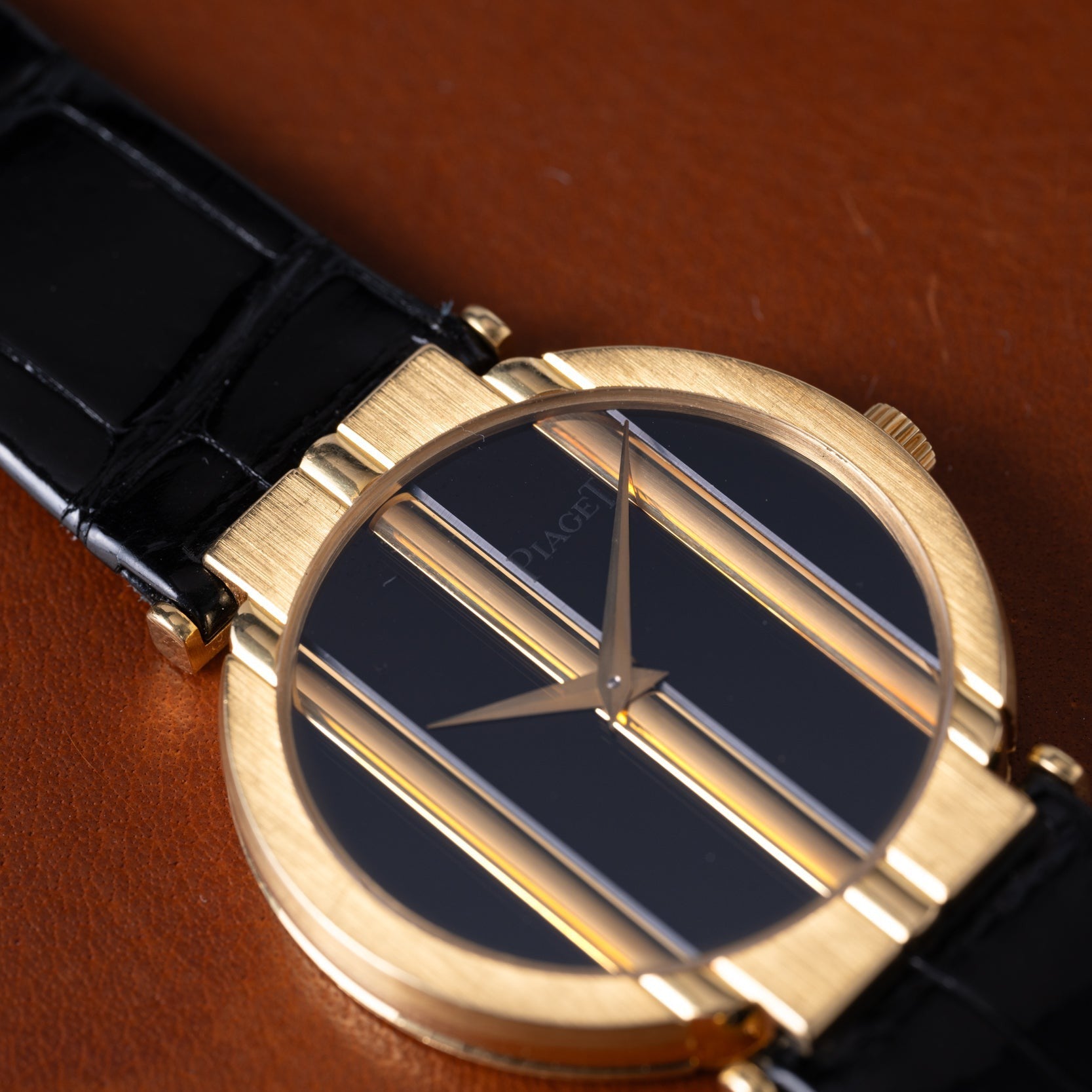 The Piaget Polo Onyx features a gold case, black dial with vertical gold bars, and a black leather strap, displayed on brown leather.