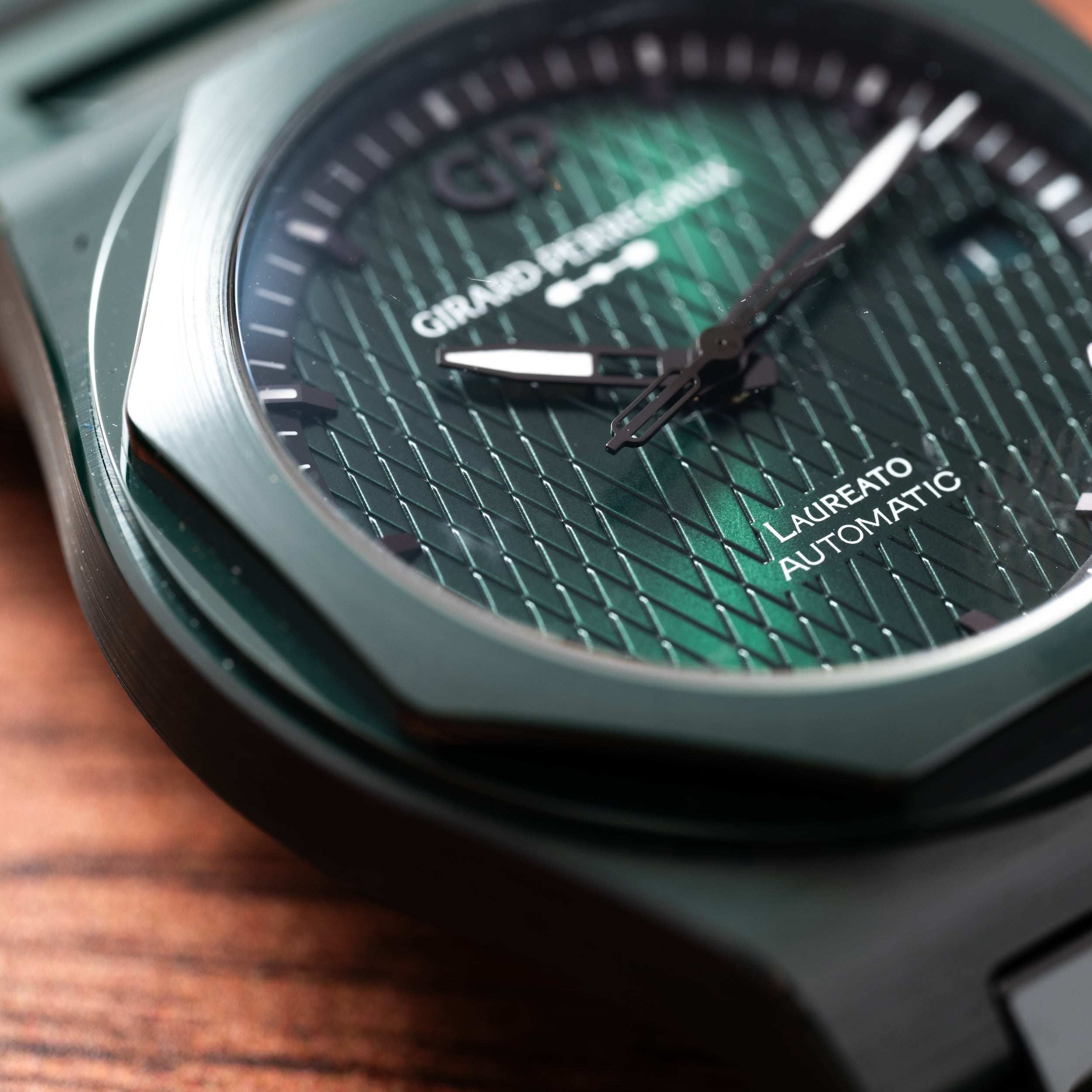 Close-up of the Girard-Perregaux Laureato Green Ceramic Aston Martin Edition watch resting on a wooden surface.