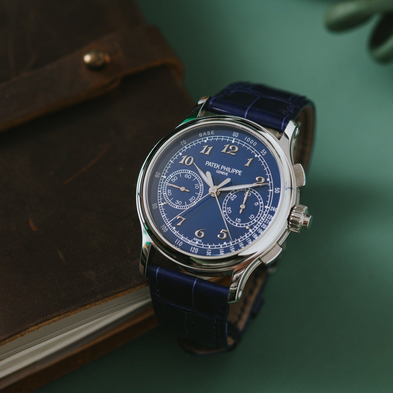 The Patek Philippe Split-Seconds Chronograph, featuring a blue dial and leather strap, rests elegantly on a brown notebook.