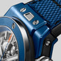 Blue ceramic watch case with brushed finish, silver accents, and black rubber strap detail visible.