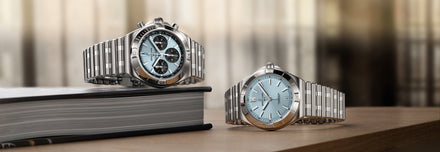 Two watches on a wooden surface with a blurred indoor background