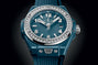Petrol blue ceramic watch with diamond-set bezel, white numerals, and silver-tone hands.