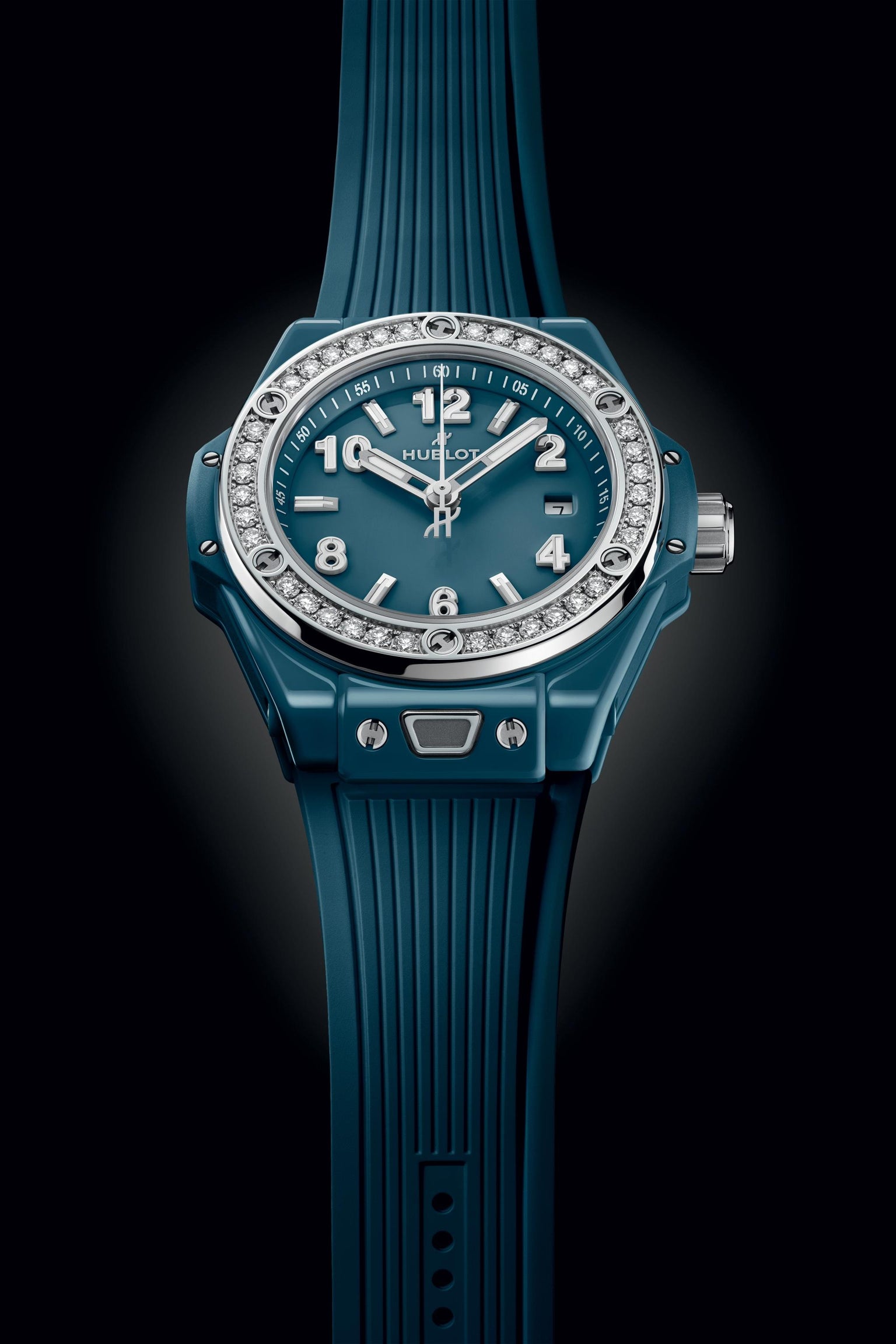 Petrol blue ceramic women's watch with diamond-set bezel, white hands and numerals on teal dial, and ribbed rubber strap.