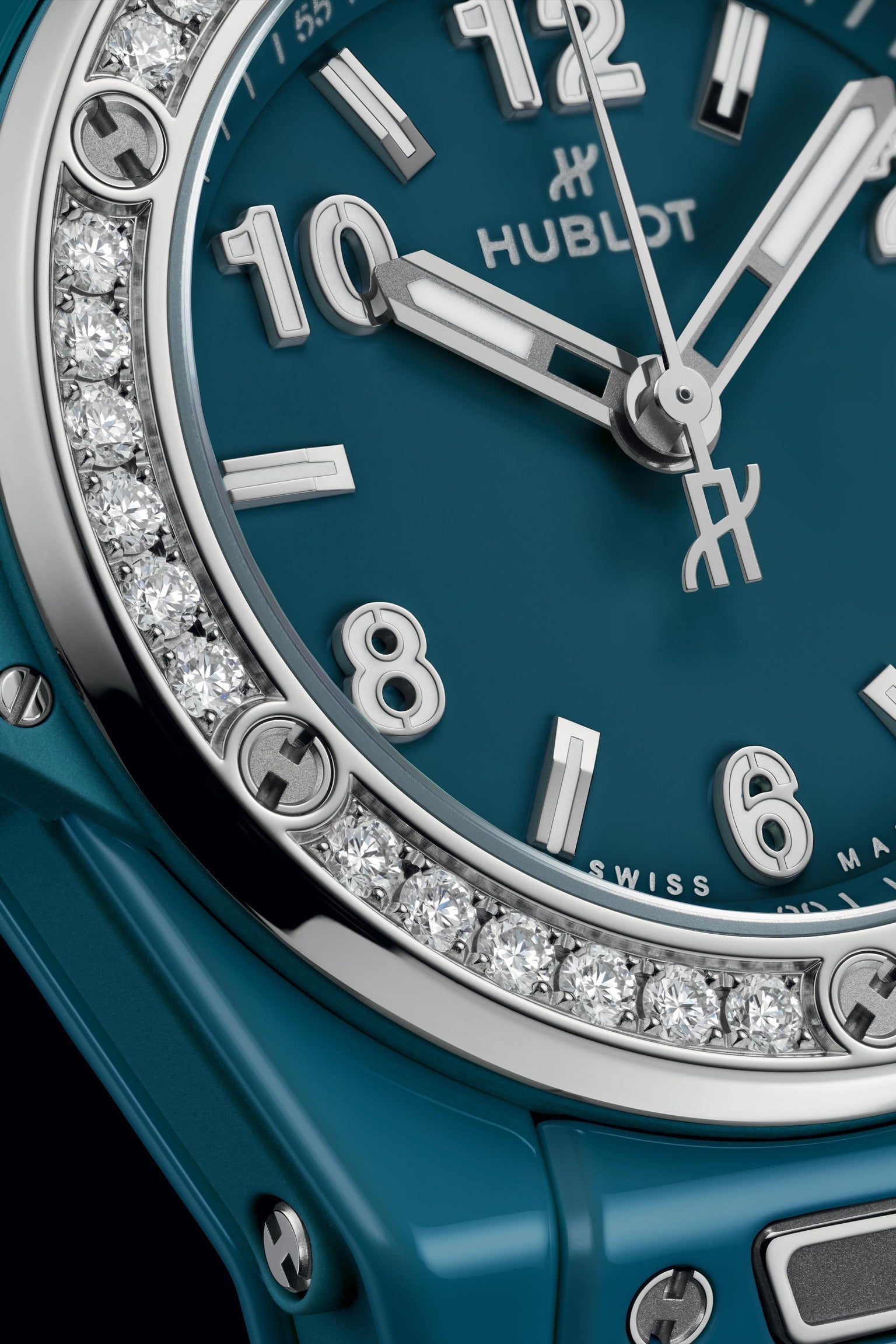 Petrol blue ceramic watch with diamond-set bezel, silver hands and numerals, Hublot branding visible on dial.