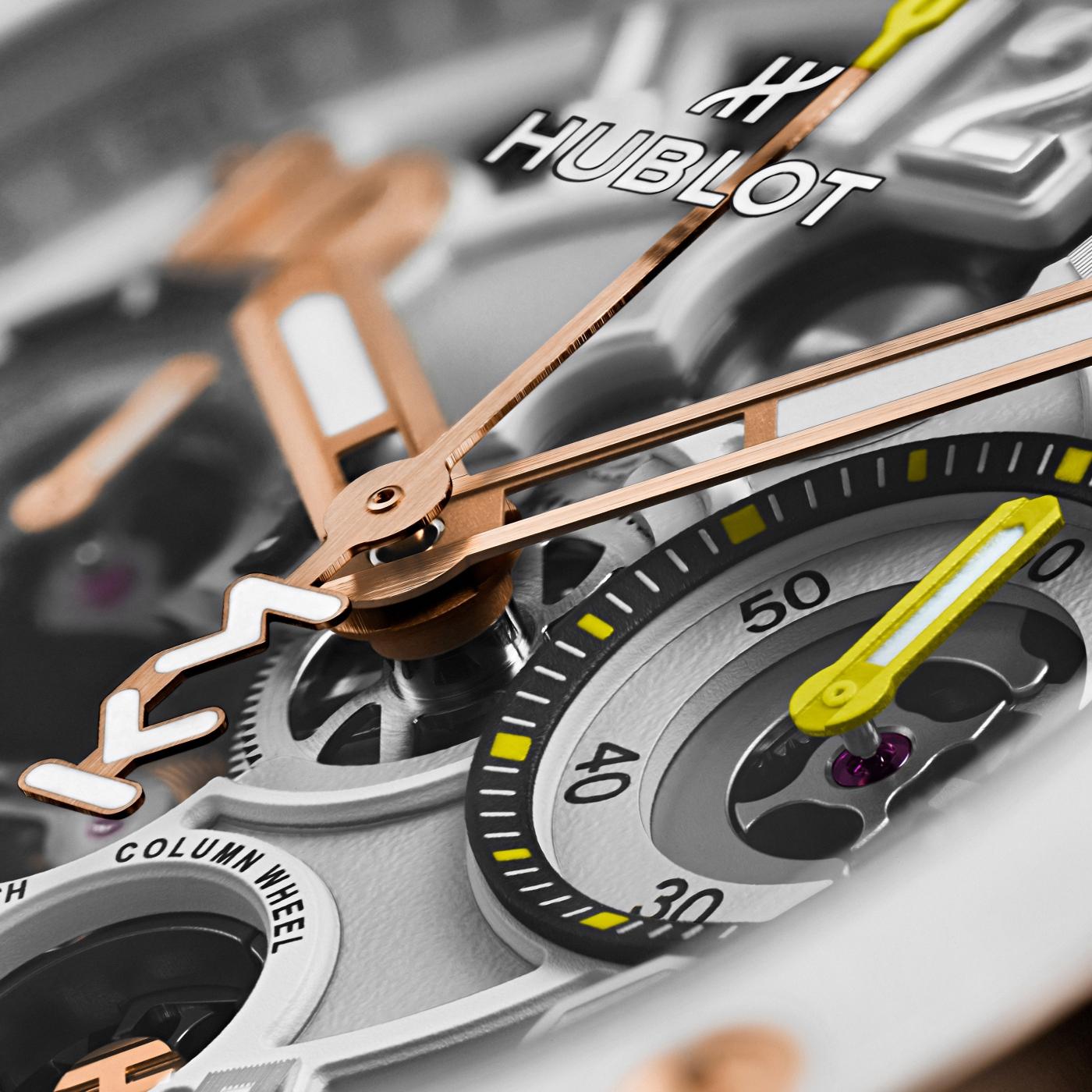 White ceramic watch dial with rose gold hands, black numerals, yellow accents, and Hublot branding visible.
