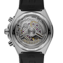 Stainless steel chronograph watch with visible mechanical movement through transparent caseback, black rubber strap.