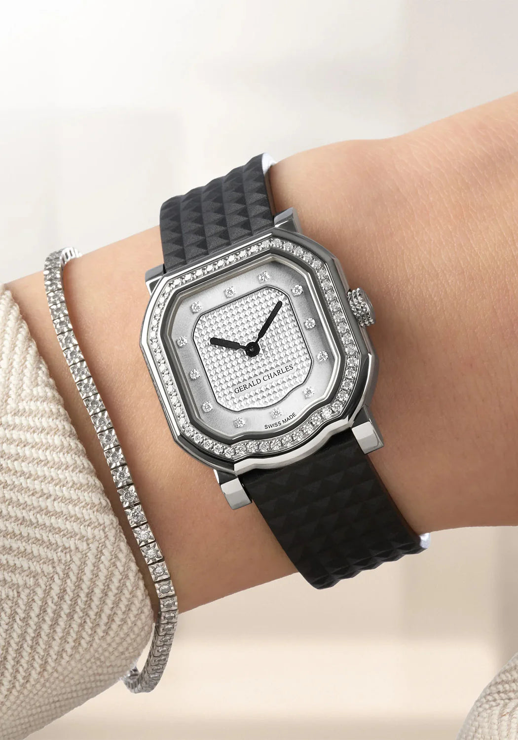 Luxury watch with black strap and diamond accents on a wrist, against a neutral background