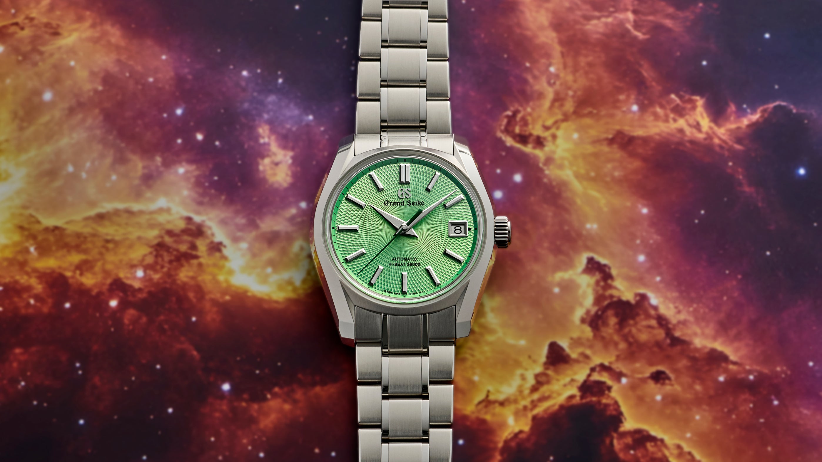 A silver wristwatch with a green face is displayed against a vibrant, colorful space background.