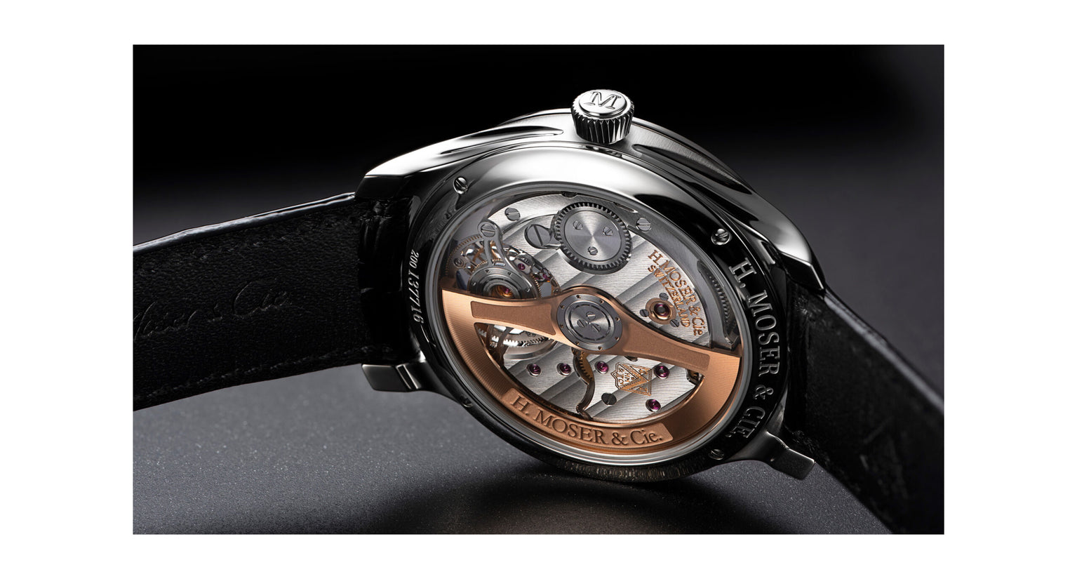 Steel watch with visible tourbillon mechanism, copper-toned rotor, black leather strap, and exposed dial displaying movement.