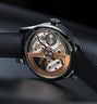 Stainless steel watch with open caseback displaying rose gold rotor, blue accents, and leather strap.