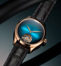 Rose gold watch with blue gradient dial, visible tourbillon at 6 o'clock, rose gold hands, and black crocodile leather strap.