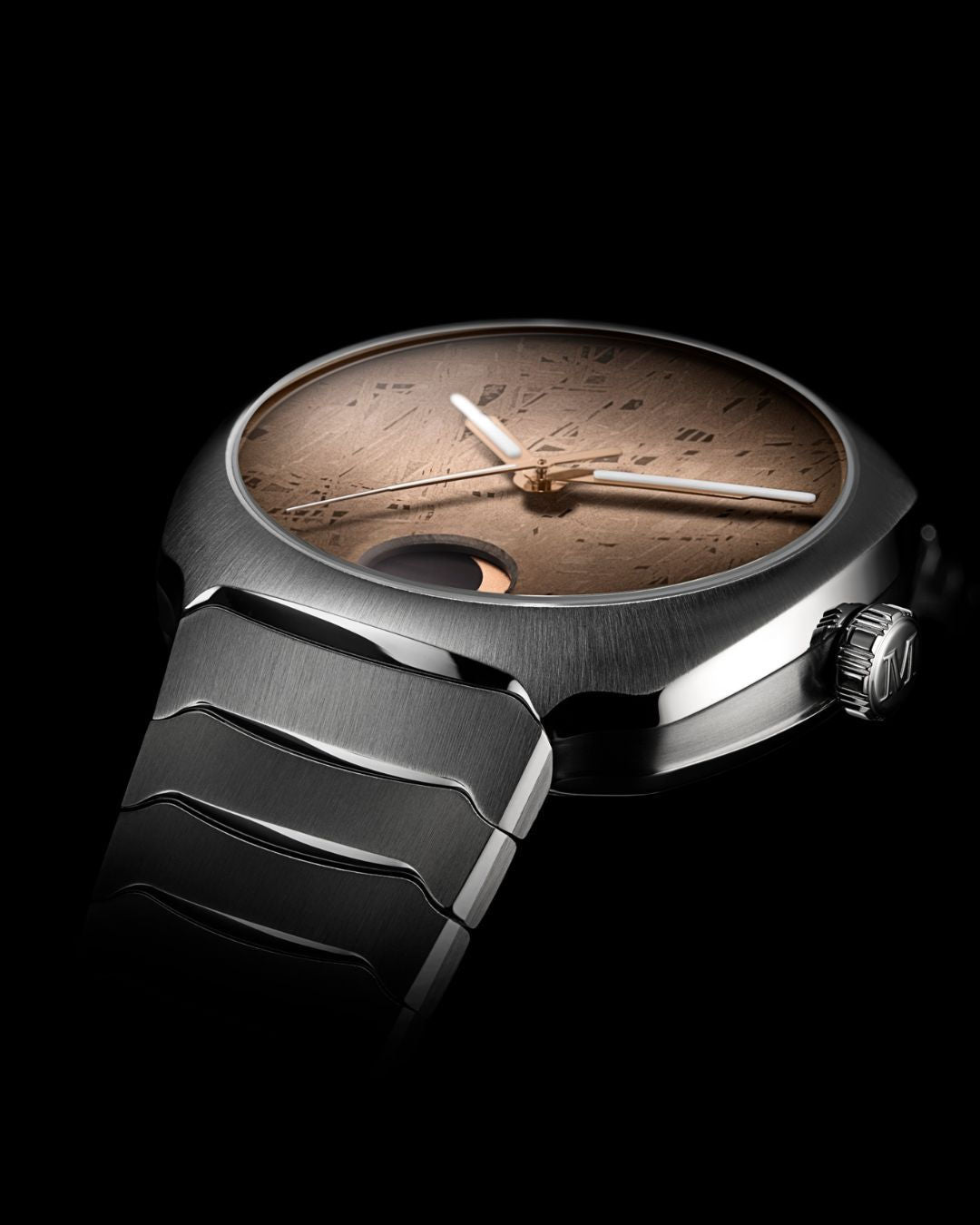 A close-up of the H. Moser & Cie Streamliner Perpetual Moon Concept Meteorite, featuring a textured Gibeon meteorite bronze dial, minimalist hands, precise moonphase display, and a sleek metallic bracelet on a black background.