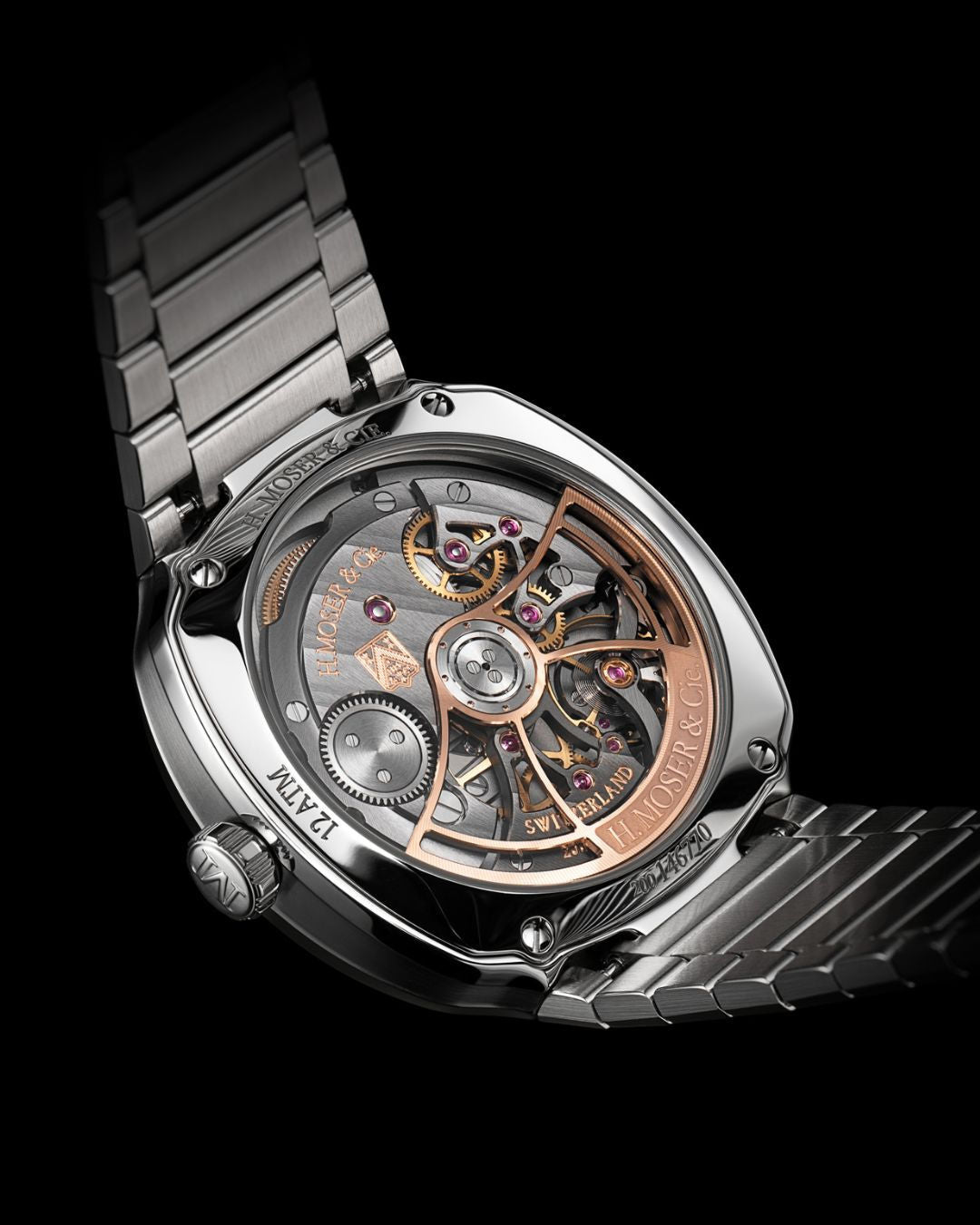 Close-up of the H. Moser & Cie Streamliner Perpetual Moon Concept Meteorite’s open back, displaying gold and silver gears, moon phase accuracy, and a stainless steel bracelet set against a black background.