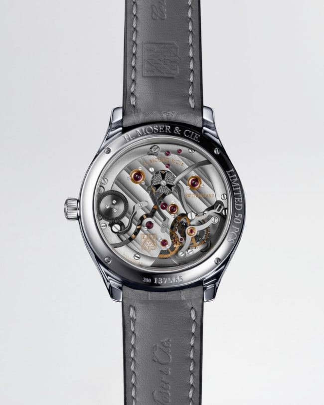 Stainless steel skeleton watch with visible tourbillon, ruby jewels, and H. Moser & Cie branding on gray leather strap.