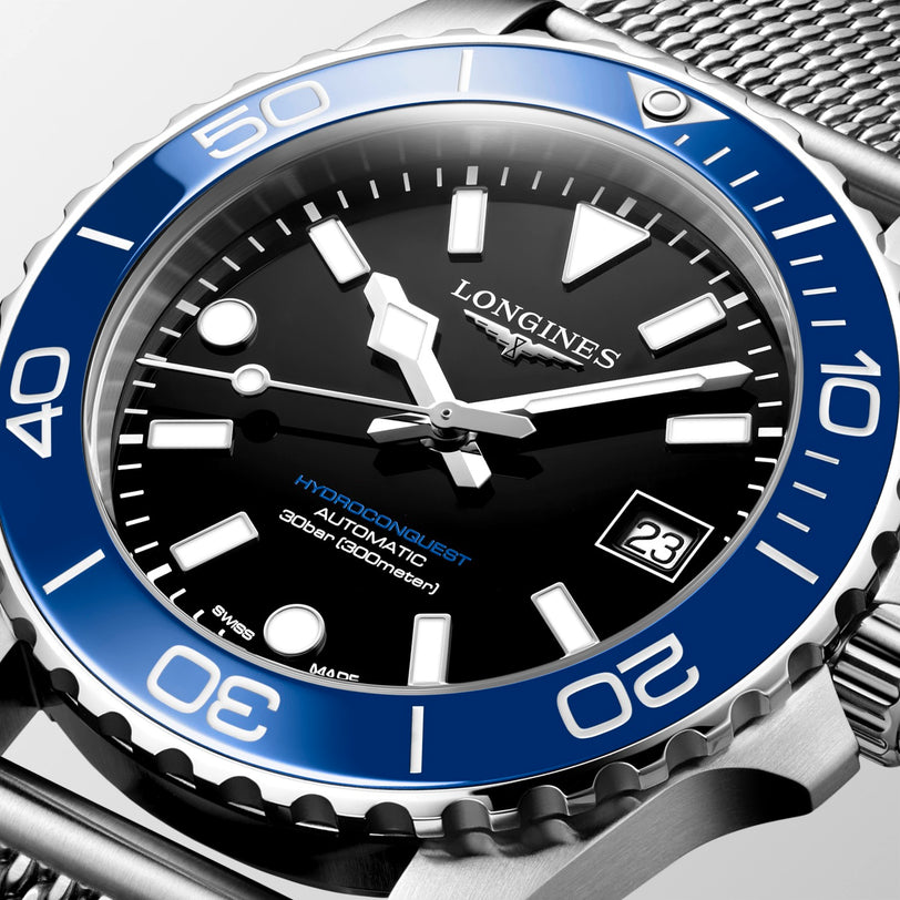 Longines watch with blue bezel and black dial on a light gray background