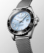 Silver Longines watch with a mesh band on a light gray background
