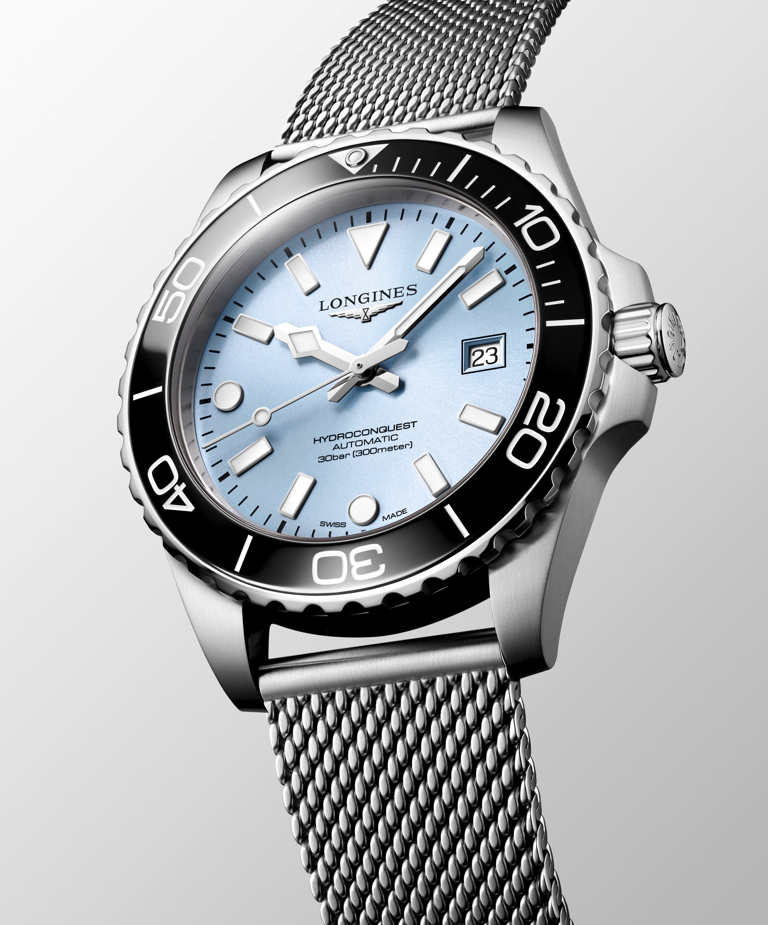 Silver Longines watch with a mesh band on a light gray background