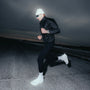 Person jogging at dusk wearing Timex Ironman watch on left wrist, black jacket, white beanie, and sunglasses.
