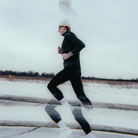Person running on a snow-covered road with a white sky