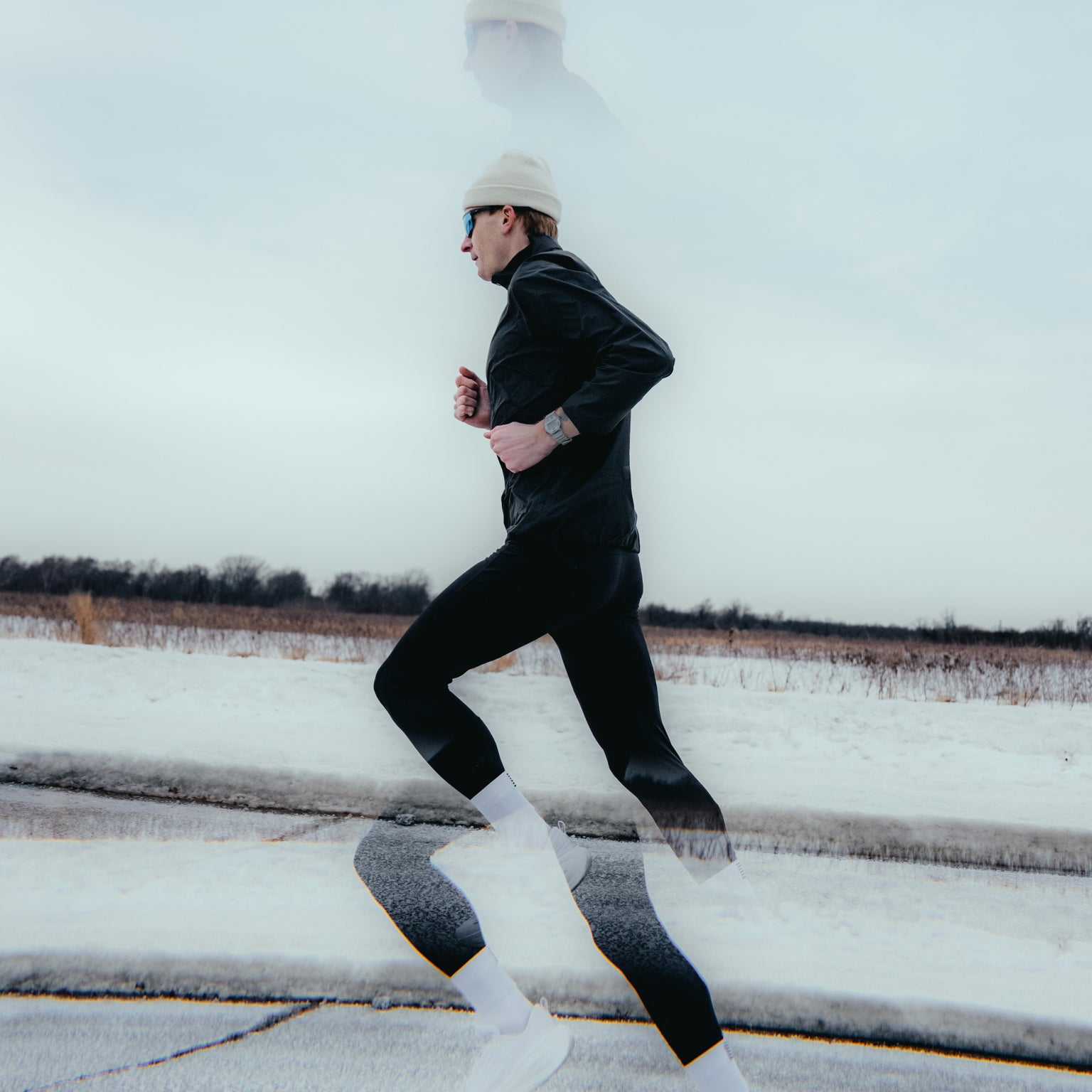 Person running on a snow-covered road with a white sky