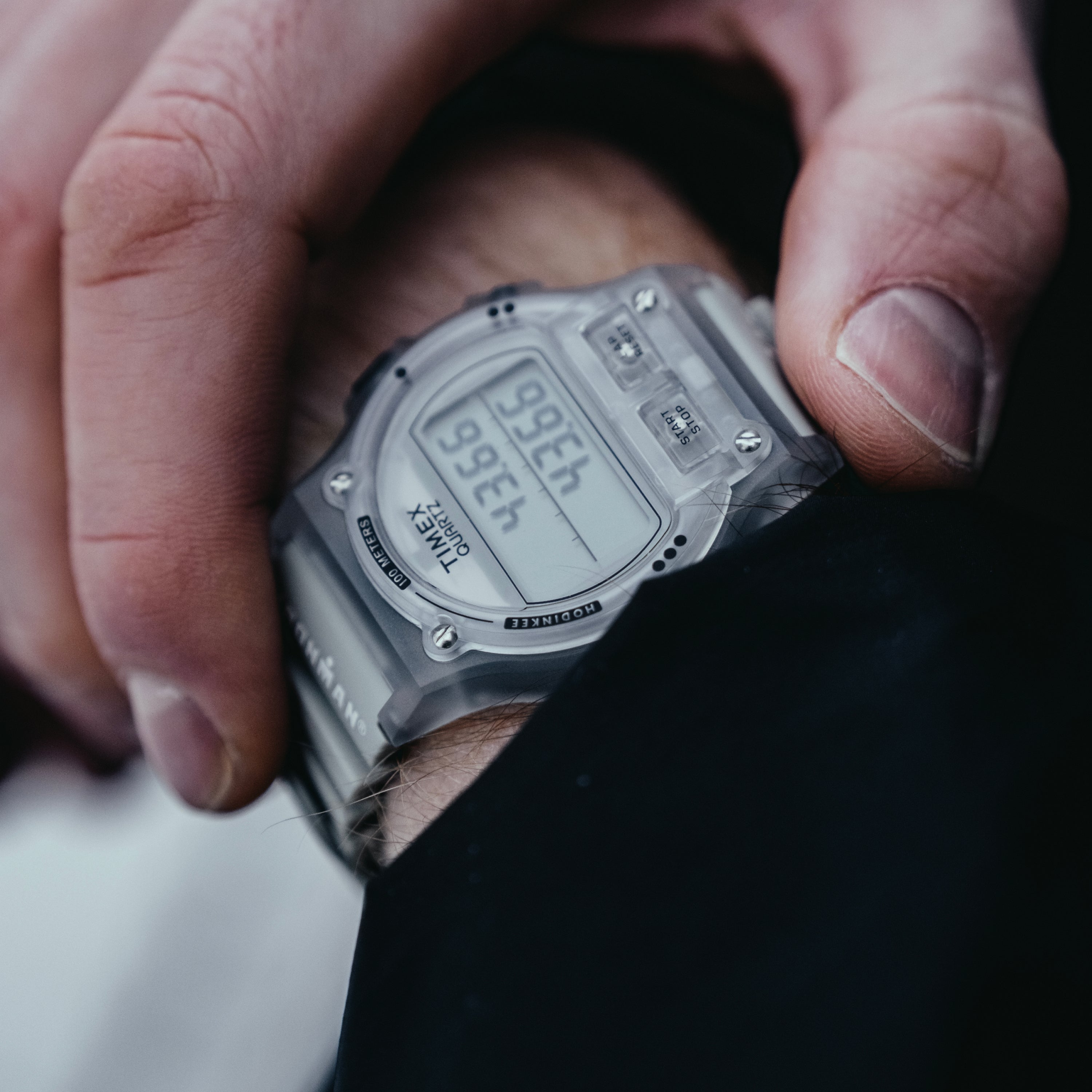 Silver digital sports watch with rectangular face and black resin band worn on wrist.