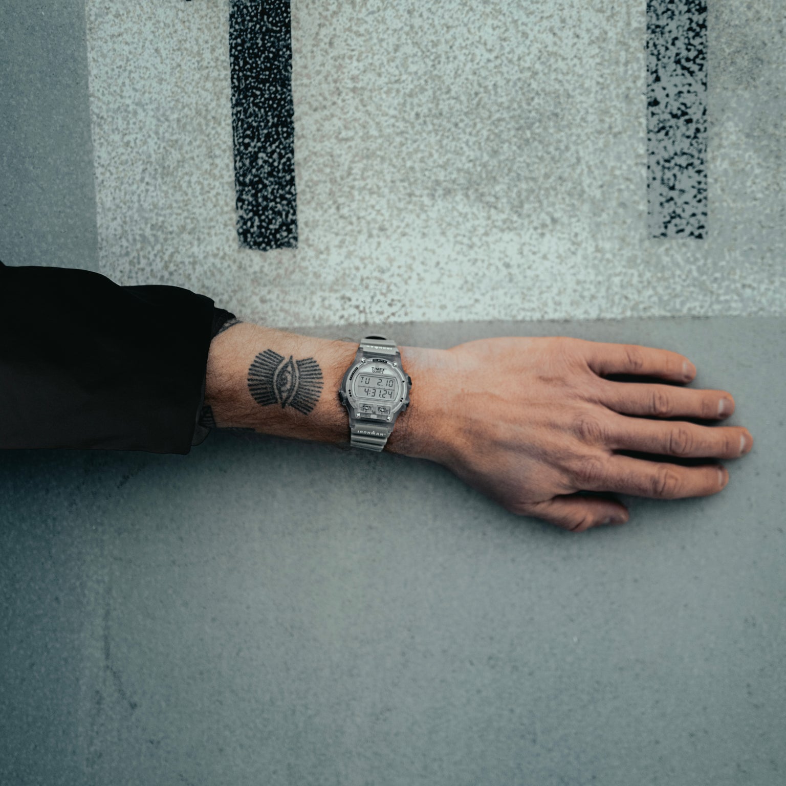 Hand with a watch and tattoo on a textured surface