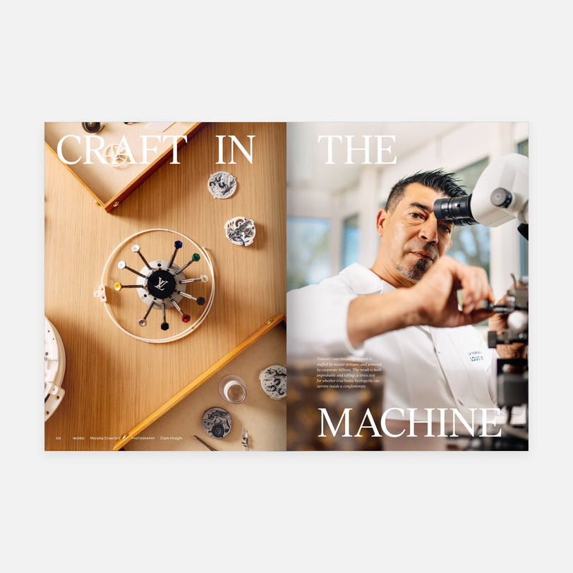 A Hodinkee Magazine Volume 15 spread shows watch parts and tools on a wooden table beside a watchmaker in a white coat at a microscope—an inside look at luxury watchmaking. Large text reads, CRAFT IN THE MACHINE.