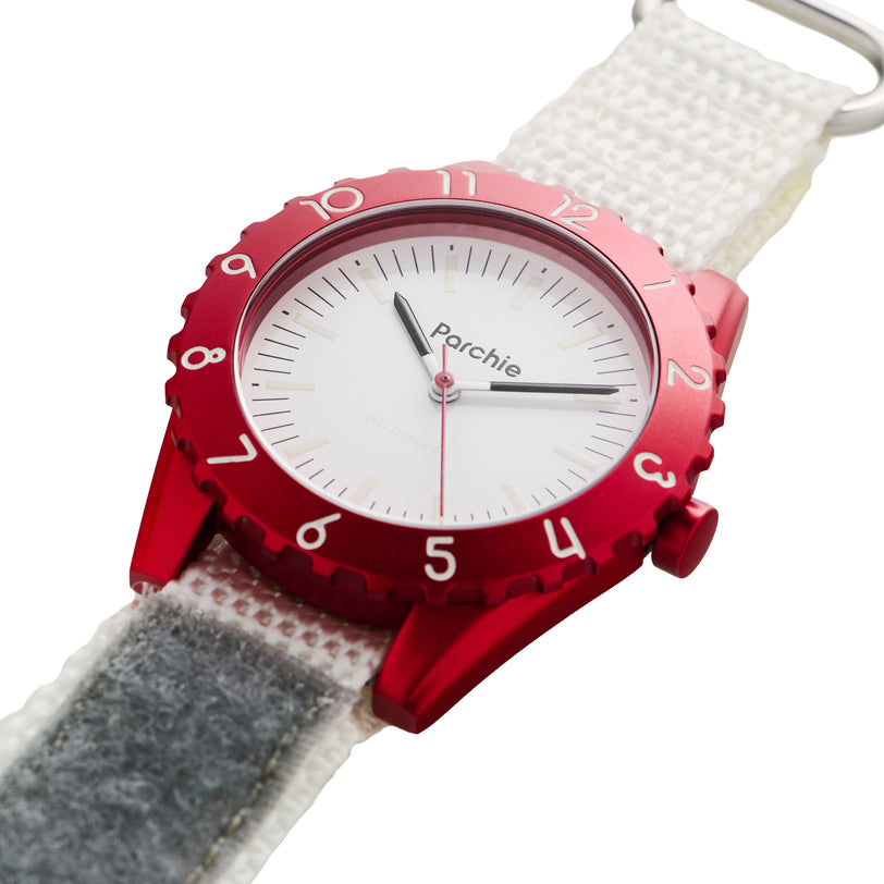 The Parchie Lunar-Time Limited Editions for Hodinkee 36 features a red bezel, white face, and white strap, with the Parchie brand name displayed on the dial.