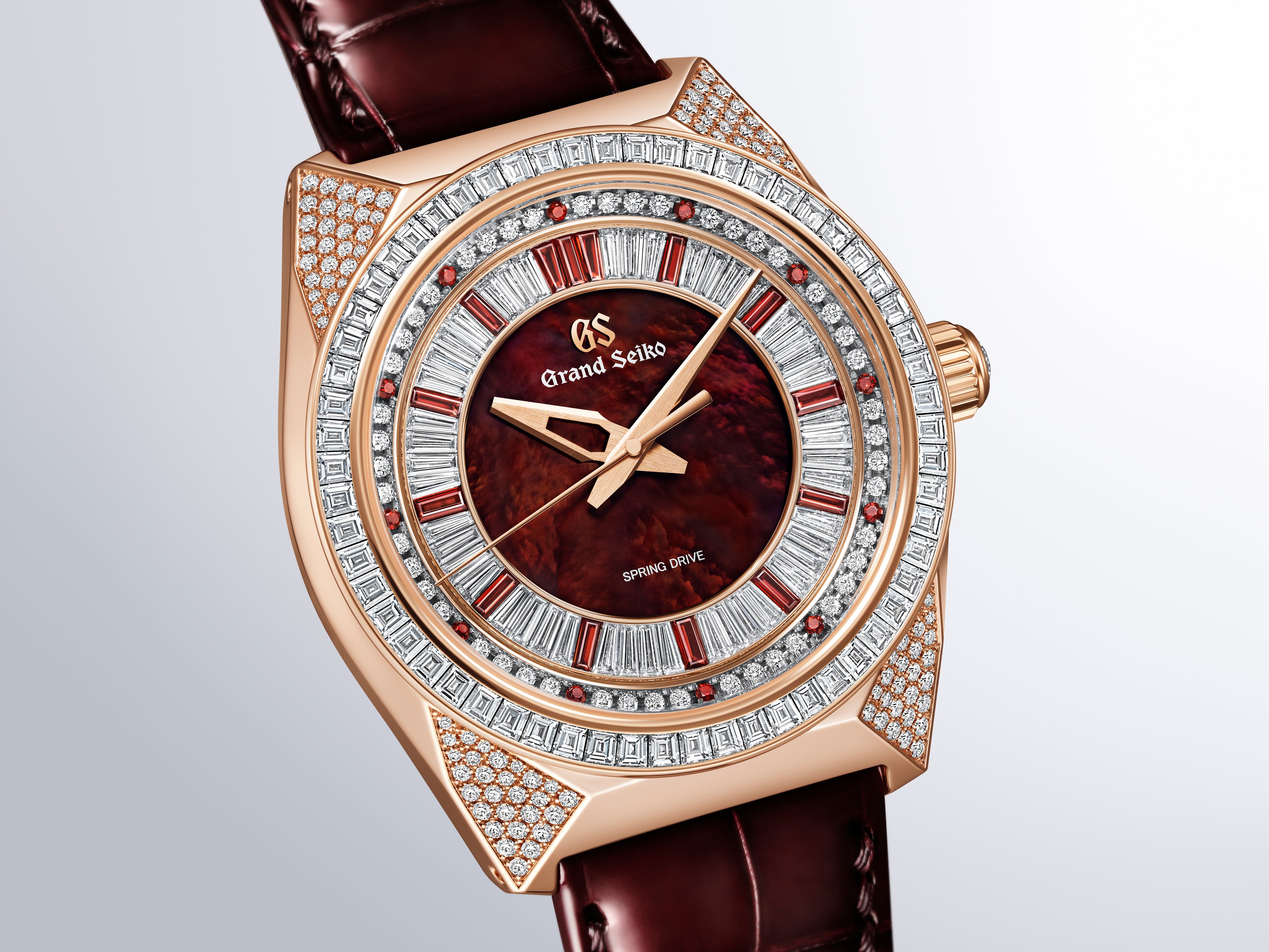 Rose gold watch with deep red dial, diamond-set bezel and lugs, baguette and round stone hour markers, burgundy leather strap