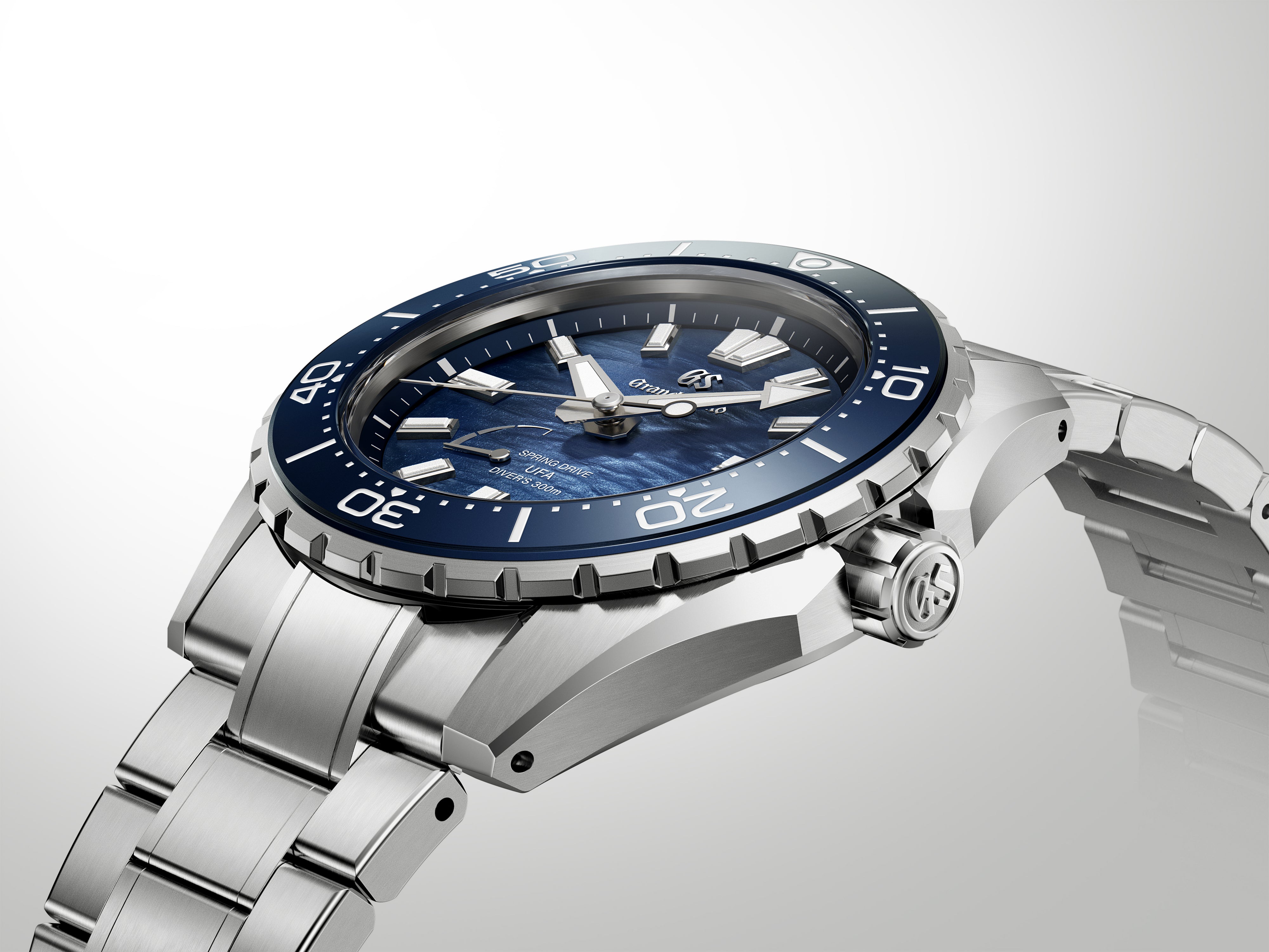 Stainless steel diver watch with dark blue dial, rotating bezel, and matching metal bracelet displayed against neutral backgr