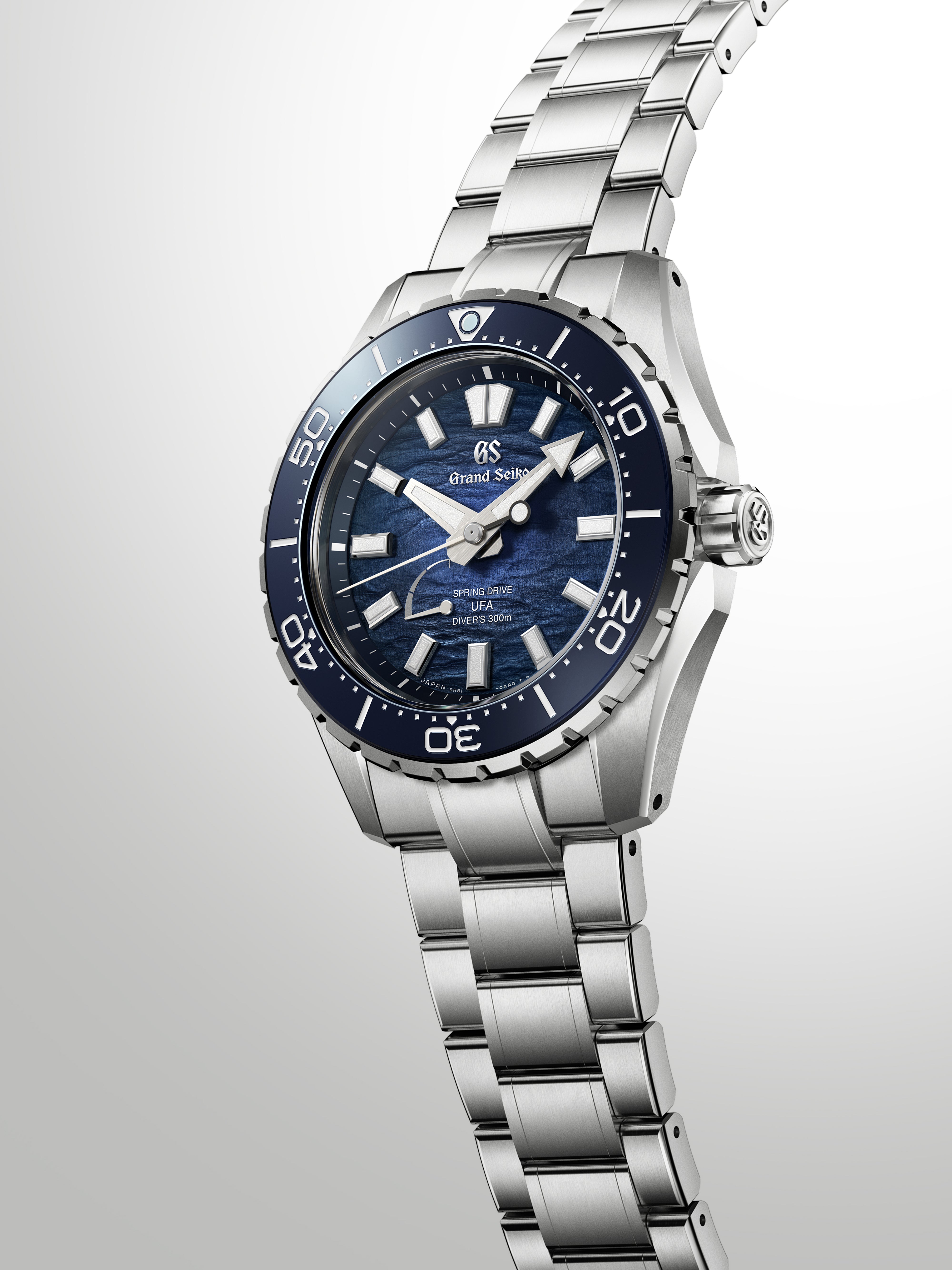 Silver and blue dive watch with dark blue dial, white hour markers, and matching blue rotating bezel on stainless steel brace