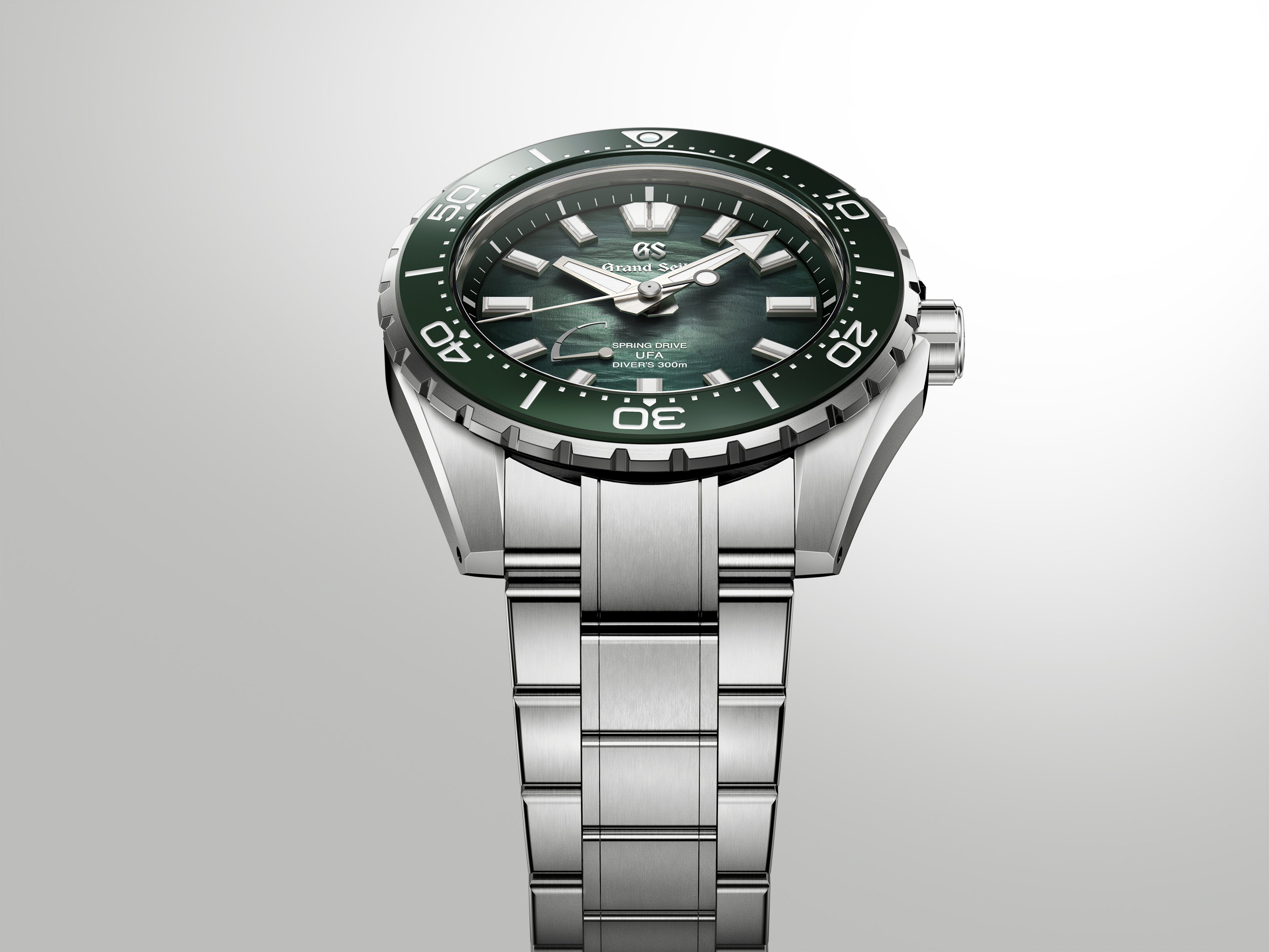 Silver stainless steel diver watch with green dial, black bezel, and matching bracelet on gray background.