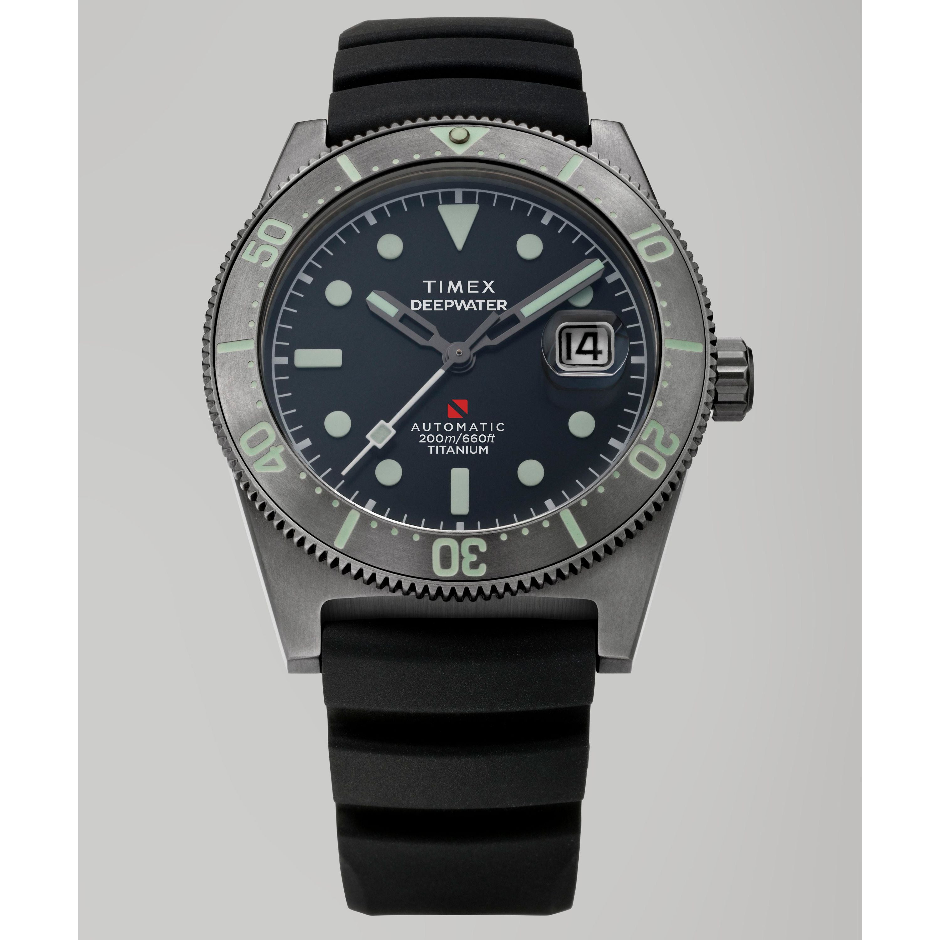The Timex G TI AU SW DEEP WTR REEF 41 BLAK DL 25 is a titanium automatic dive watch with a black dial, bold white markers, date at 3 o'clock, rotating bezel, black rubber strap, and "Automatic Titanium" text.