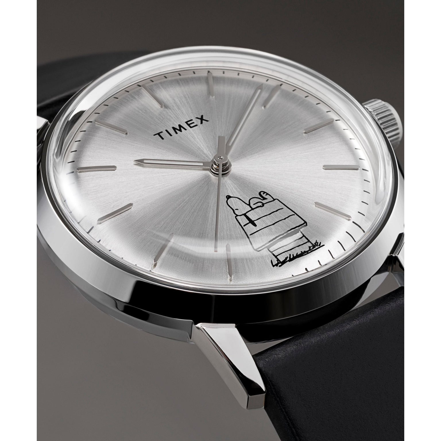 A close-up of the Timex x Peanuts® Marlin® Automatic 75th Anniversary Edition by Timex with a silver case, black leather strap, and minimalist dial featuring Snoopy lying on his doghouse for a stylish, playful touch.